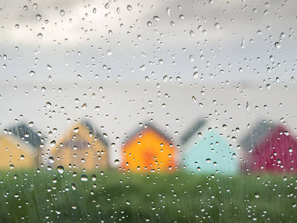 Rain drops on a car window at an English seaside Rain drops on a car window on a wet day at the seaside in Herne Bay, Kent, Uk. Painted colourful beach huts can be seen in front of a grey sea. herne bay stock pictures, royalty-free photos & images