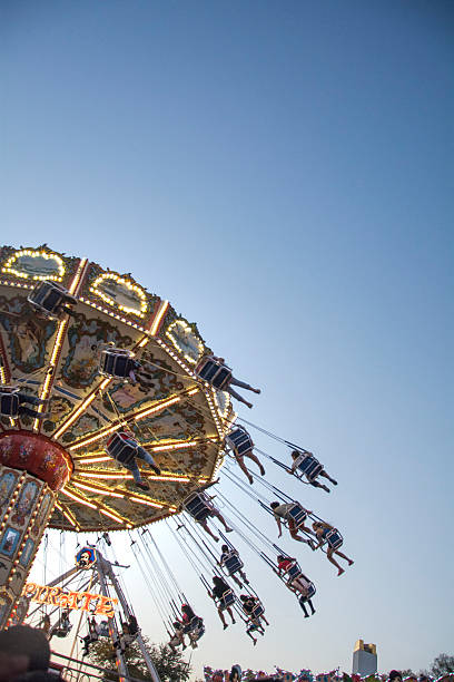 adultos jóvenes balanceo en columpios en la feria estatal de texas - dallas texas texas ferris wheel carnival fotografías e imágenes de stock