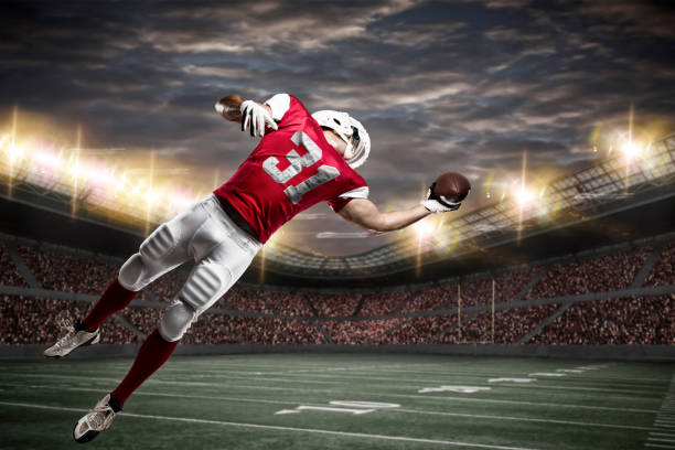 Football Player Football Player with a red uniform catching a ball on a stadium. Touchdown stock pictures, royalty-free photos & images