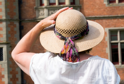 Senior 65 year old woman with straw hat looking at historic building