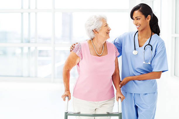istock Nurse Assisting Elderly Woman With Walker While Looking At Her 503488741