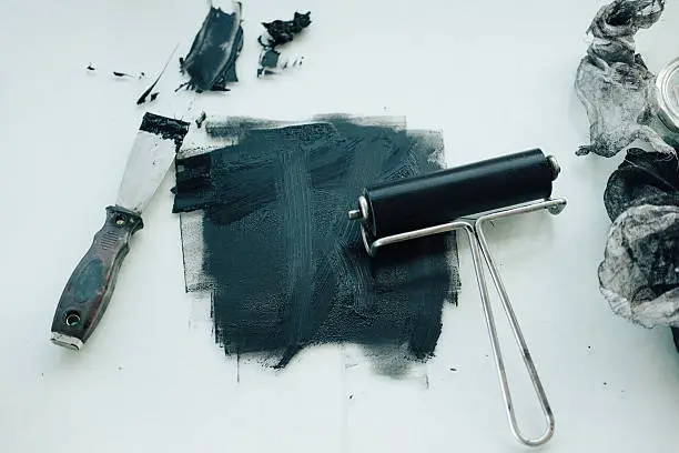 Photo of Black printmaking ink with roller and spatula