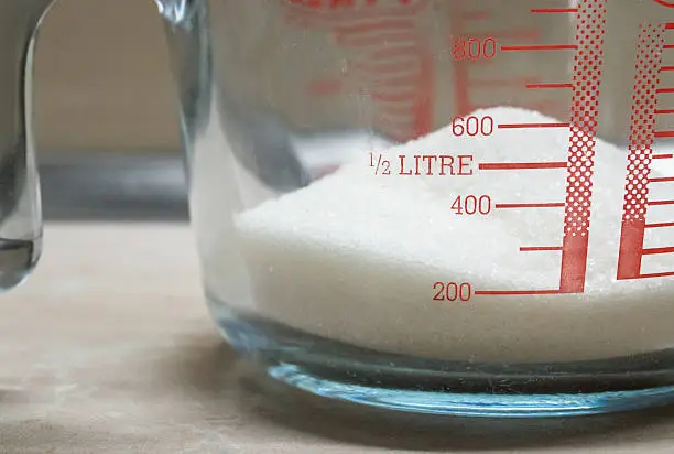 Some white sugar in a glass measuring jug.
