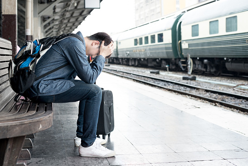 Asian depressed traveler waiting at train station after mistakes a train