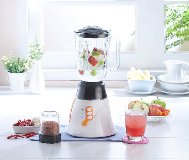 Woman making cream soup from vegetables in blender.
