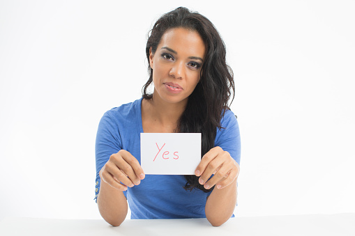 Smiling woman  showing a white card with word Yes