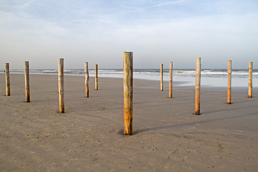 Wooden poles on a beach, remainders of a beach restaurant in winter