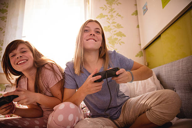 девушка jokingly увеличивая ее подруга, играя в компьютерные игры - video game friendship teenager togetherness стоковые фото и изображения