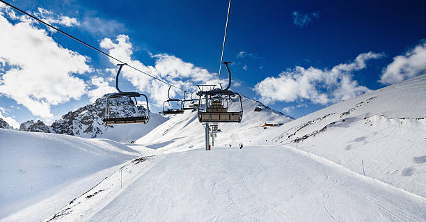Winter mountains panorama with ski slopes and ski lifts. Winter mountains panorama with ski slopes and ski lifts. Skiers going down the slope under ski lift. almaty photos stock pictures, royalty-free photos & images