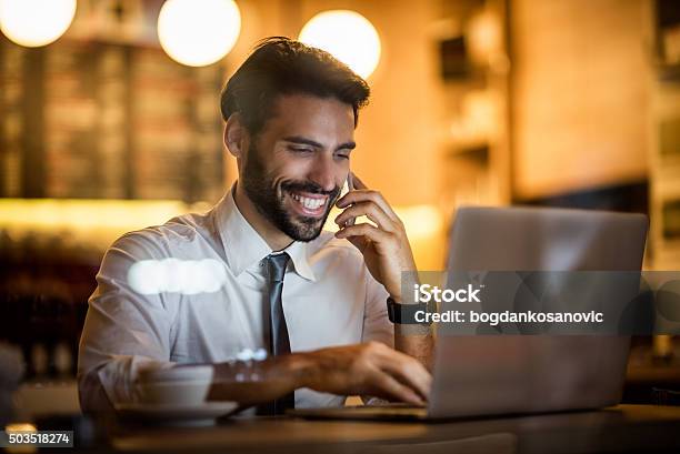 Businessman With Mobile Phone And Laptop Inside Coffee Shop Stock Photo - Download Image Now