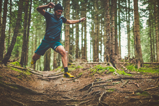 A man exercise trail running in a green and wet forest