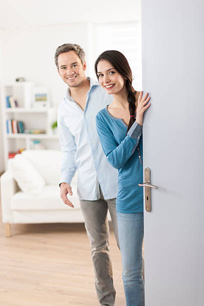 istock Cheerful couple inviting people to enter in home 503524681