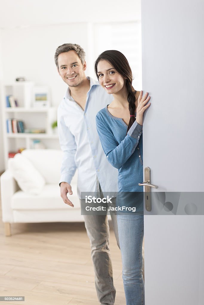 Cheerful couple inviting people to enter in home 30-34 Years Stock Photo