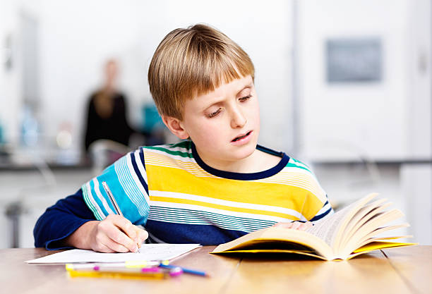 istock Schoolboy sitting at kitchen table concentrating on his homework 503529895