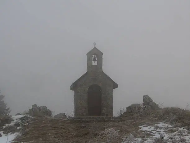 Small stone chapel in the misty mountain.