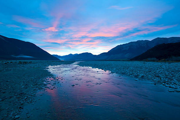 Dawn breaks over Arthur's Pass and the the Southern Alps on New Zealand's South Island, and the Waimakariri River flows off towards the rising sun.