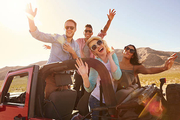 istock Friends On Road Trip Standing In Convertible Car 503535574
