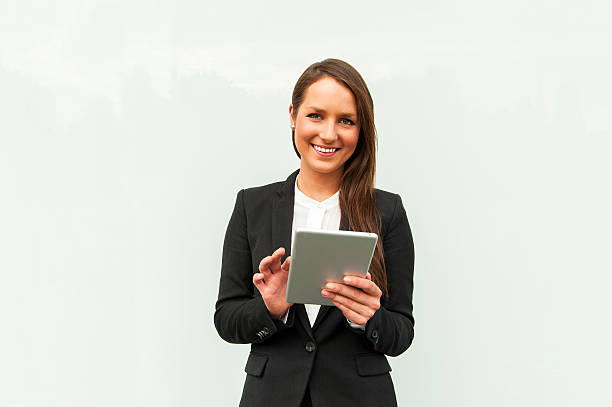 Young businesswoman touching tablet by the wall in the city. stock photo
