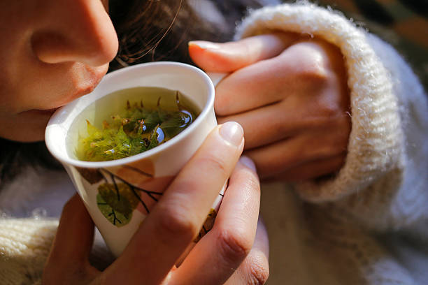 Sage tea with woman hand and woman lips A young woman on the couch and with sage tea on the hand. herbal tea stock pictures, royalty-free photos & images