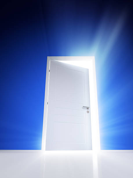 istock Open white door with rays of light on blue wall 503541362