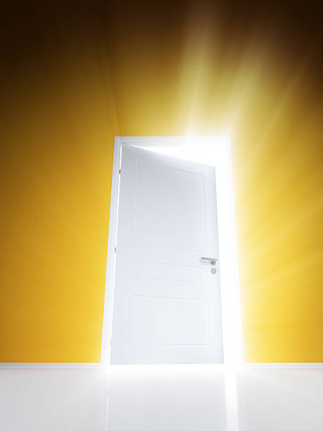 istock Open white door with rays of light on orange wall 503541734