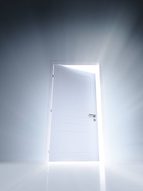istock Open white door with rays of light on blue wall 503542382