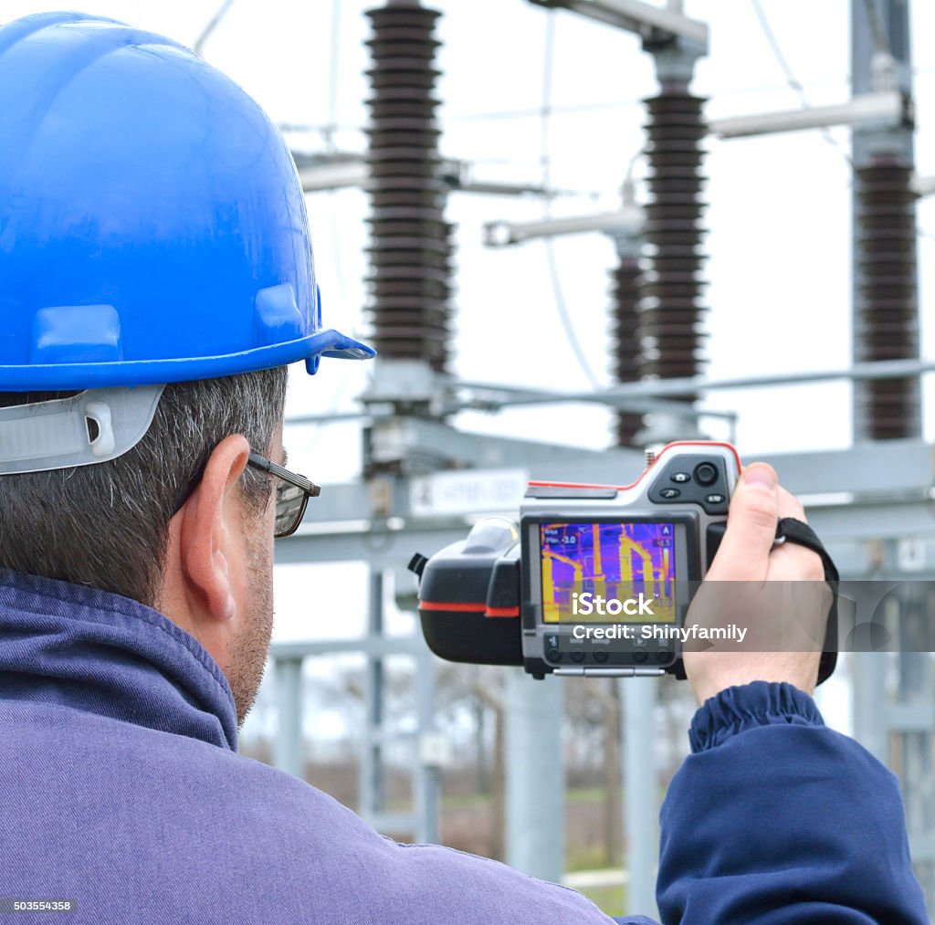 Thermal Imaging and Camera Engineer works with thermal infrared camera. Electrician is in thermographic inspection in power substation, he checks temperature and heating of transformer in power substation. Thermal Image Stock Photo