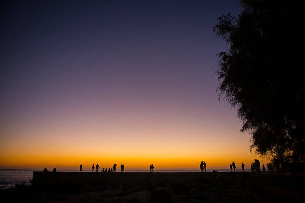 Groups of unidentifiable people watching the spectacular sunset on New Years day in Maspolomas, Gran Canaria, Spain. 
