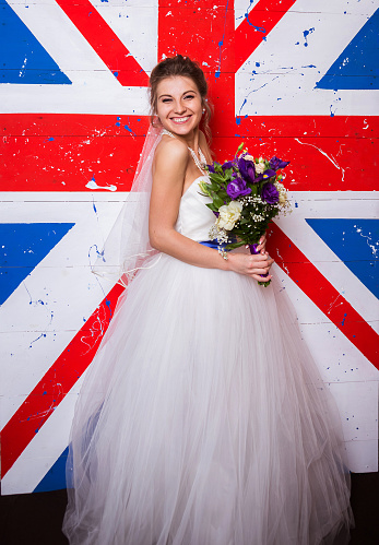 Young beautiful bride posing near english flag background