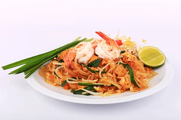Fried noodle Thai style with prawns, Stir fry noodles with shrimp in padthai style on table. Front view isolate white , brown background