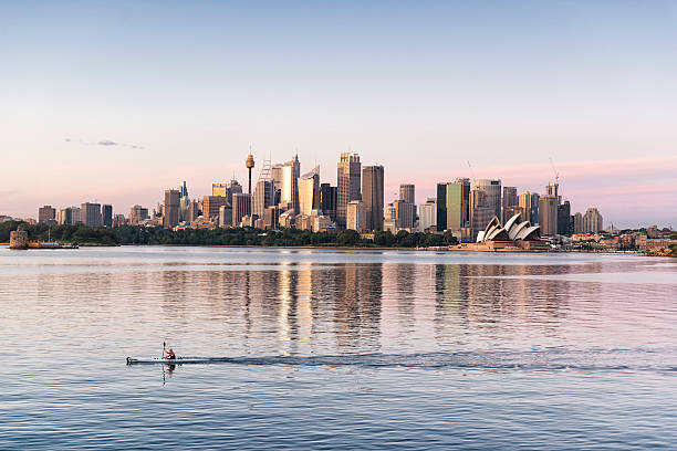 Sydney sunrise moments Sydney, Australia - November 18, 2015: A kayaker is passing by while the sunset is on the Sydney skyline. Central Business District and the Opera House is in the background.  australian culture photos stock pictures, royalty-free photos & images