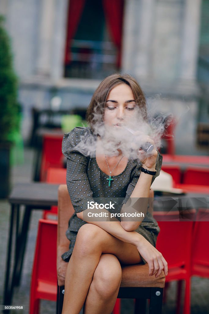 girl with E-cigarette beautiful brunette smoke electronic cigarette on the summer terrace of restaurant Addiction Stock Photo