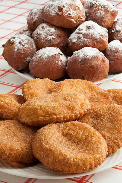 Heap of sugared fried fritters called oliebollen and appelflappen on a dish