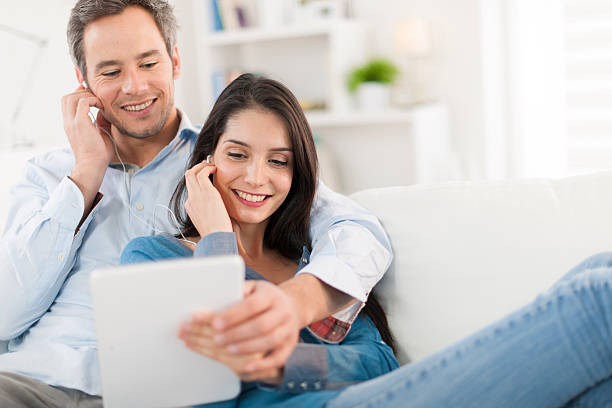 istock cheerful couple sharing music on digital tablet in sofa 503565669