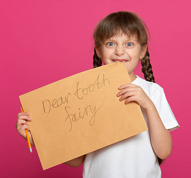 istock lost tooth girl portrait, studio shoot on pink background 503566308