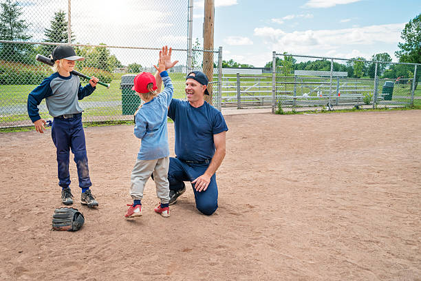 mais cinco entre pai e filho mais novo depois de beisebol jogo. - sports uniform fotos imagens e fotografias de stock