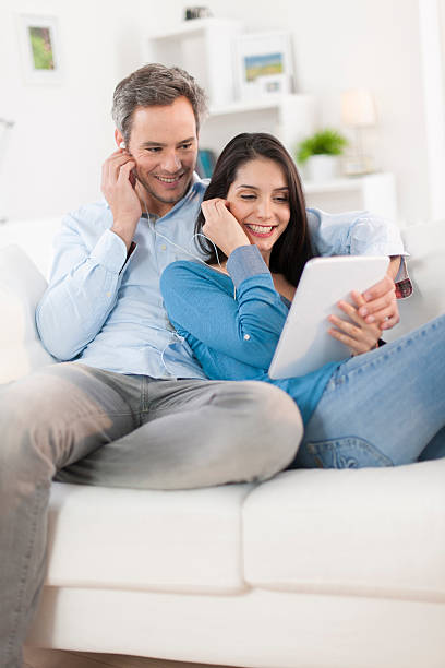 istock cheerful couple sharing music on digital tablet in sofa 503567883
