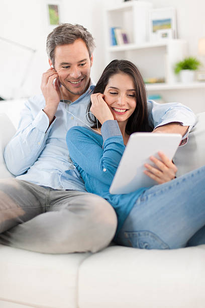 istock cheerful couple sharing music on digital tablet in sofa 503567891