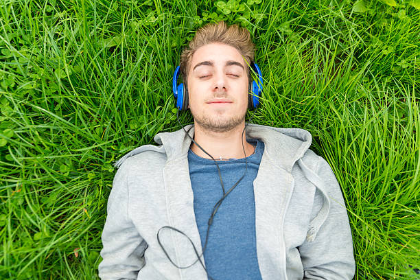 Young man with headphone listening to music in park stock photo