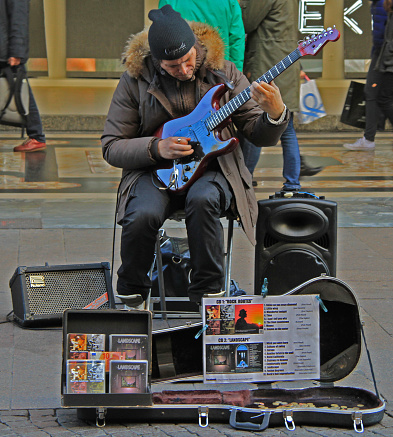 Milan, Italy - November 27, 2015: street musician is playing guitar in outdoor in Milan, Italy
