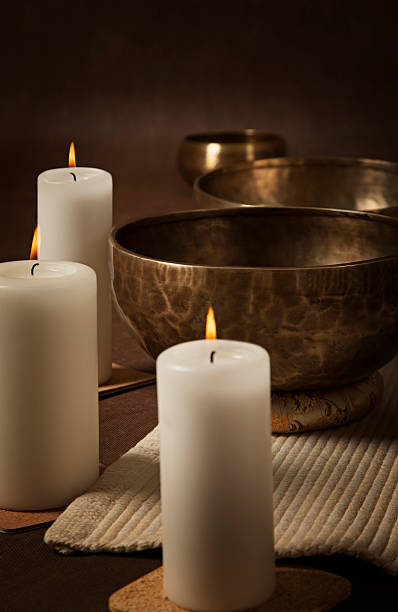 Vertical shot of Tibetan singing bowls with burning candles close-up.