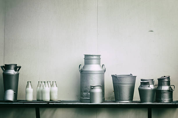 Old milk jugs, cans and bottles Old milk jugs, cans and bottles at dairy farm butter churn stock pictures, royalty-free photos & images