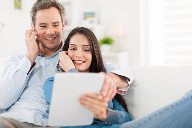istock cheerful couple sharing music on digital tablet in sofa 503597465