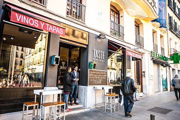 Madrid, Spain - December 22, 2013: Wine Tasting Gallery Vinos y Tapas in the center of Madrid, Spain. Two men standing at the entrance. People walking on the street.