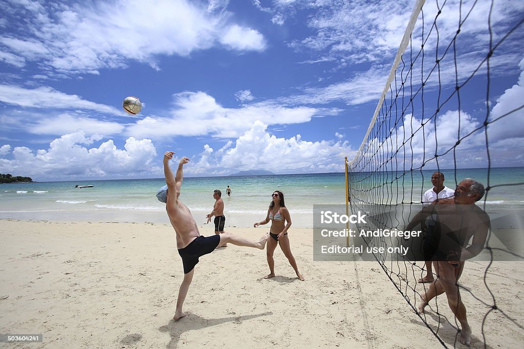 Group of friends plays volleyball on the beach. Victoria, Seychelles - March 16, 2014: Group of friends plays volleyball on the beach. A man missed the ball. Activity Stock Photo