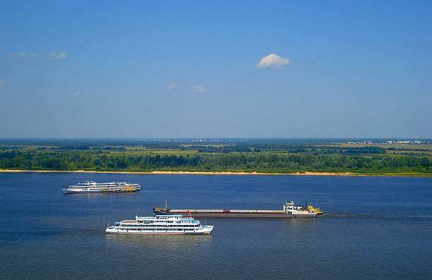 Barge and ships sailing on the Volga river. Panoramic views over the plain which merges with the sky on the horizon. Nizhny Novgorod. Russia