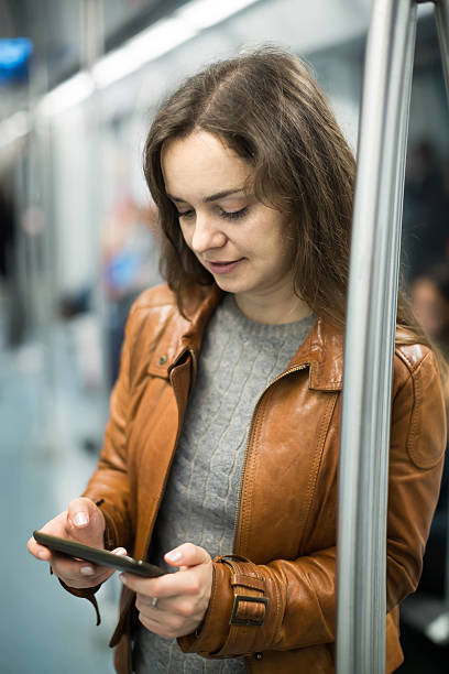istock brunette girl using cell phone and smiling at subway 503612762