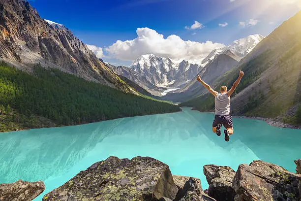 Photo of Beautiful mountain landscape with lake and jumping man