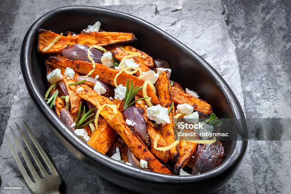 Sweet Potato Fries with Red Onion Feta Cheese and Lemon Spicy sweet potato fries with red onion, feta cheese and lemon.  Aerial view over slate. French Fries Stock Photo