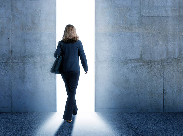 istock Businesswoman walking into bright light from inside building 503621280